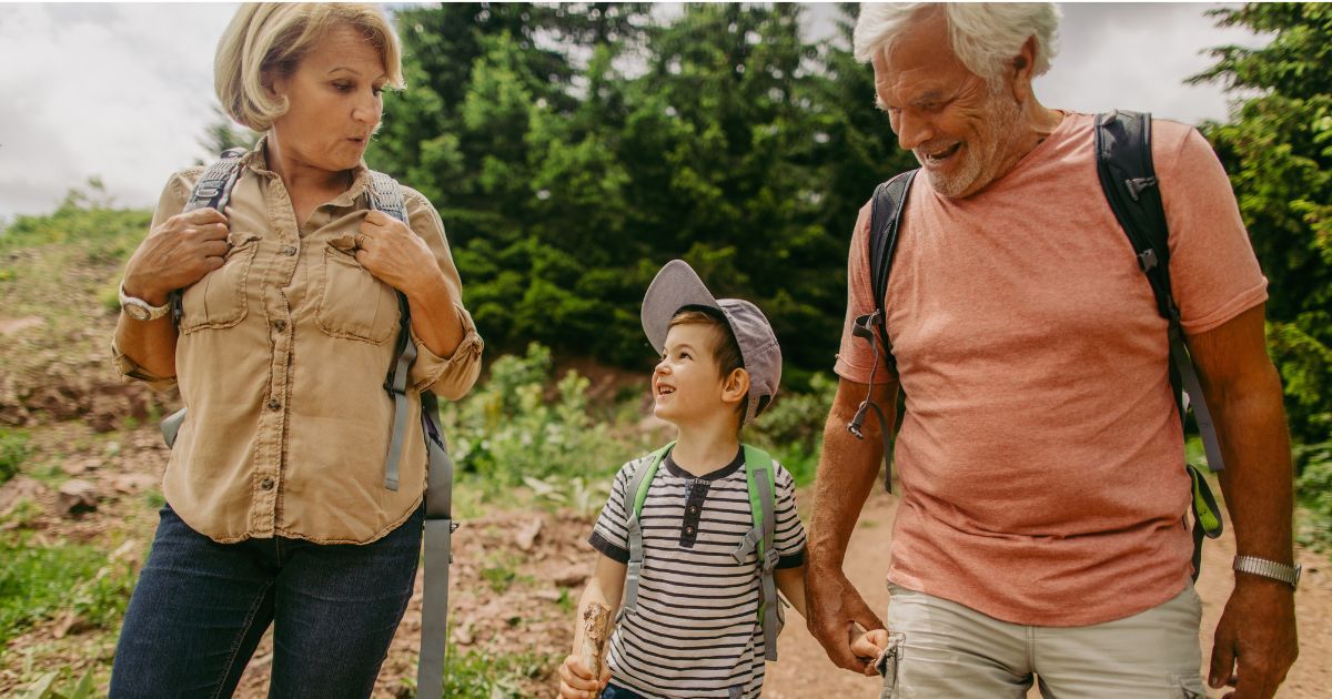 A retired couple hiking outdoors with their young grandchild